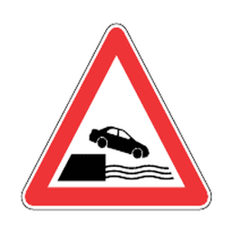 Road runs alongside water — Saudi road sign
